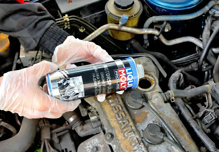 Ręce w rękawiczkach trzymają puszkę Liqui Moly Engine Flush, gotową do użycia w silniku.