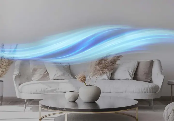 Ondas de aire azul fluyen sobre un sofá moderno, sugiriendo la acción de un ionizador de aire casero purificando el ambiente.
