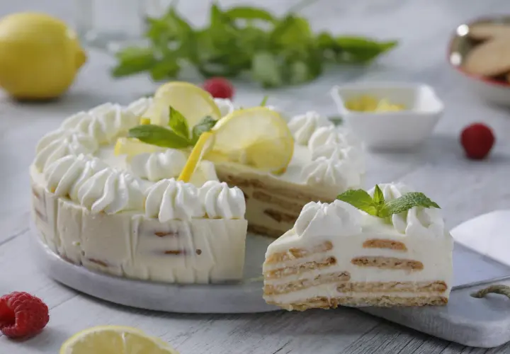 Delicioso postre de limón con leche condensada y galletas, decorado con crema batida, rodajas de limón y menta.