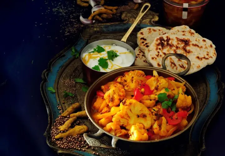 Aksamitne curry z kalafiora z mleczkiem kokosowym, podane z chlebkami naan i jogurtem.