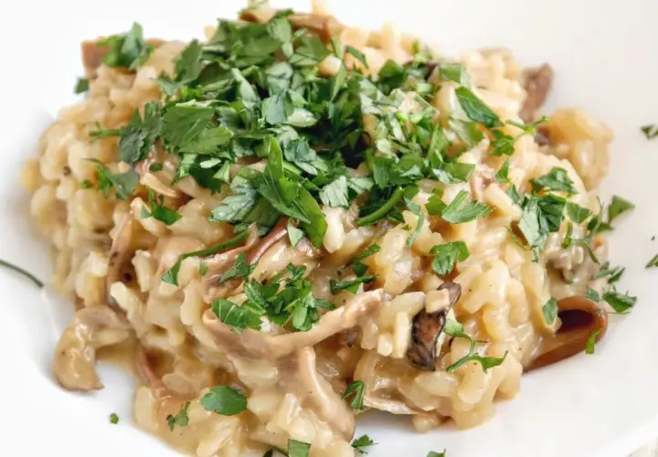 Kremowe risotto z grzybami, posypane świeżą natką pietruszki. Idealne na jesienny obiad.