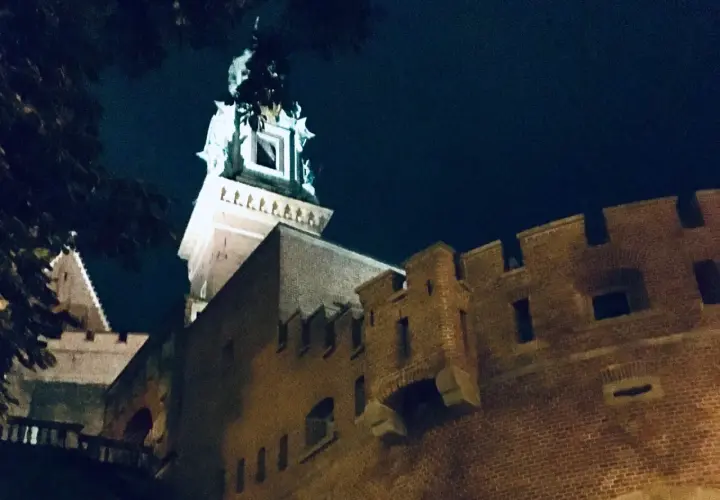 Wieczorne ciekawostki o Krakowie: Wawel nocą, z murami i wieżą oświetloną blaskiem księżyca.