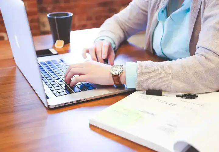 Osoba pracuje na laptopie, obok leży notatnik z długopisami. Różne rodzaje wykształcenia można zdobywać w ten sposób.