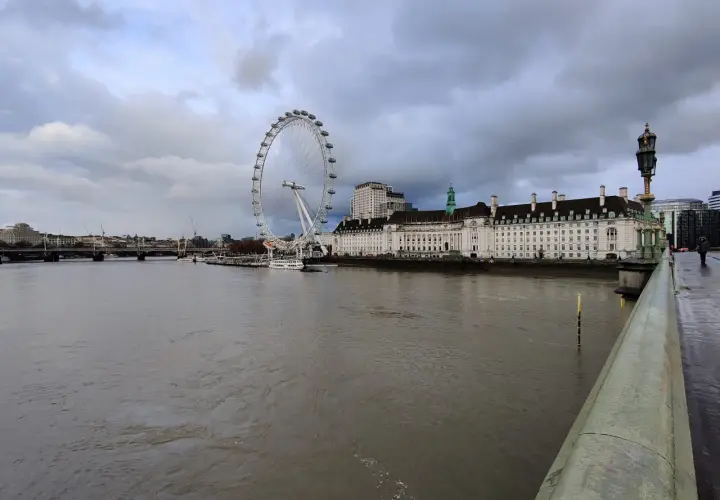Widok na Tamizę z charakterystycznym London Eye w tle, pod pochmurnym niebem.