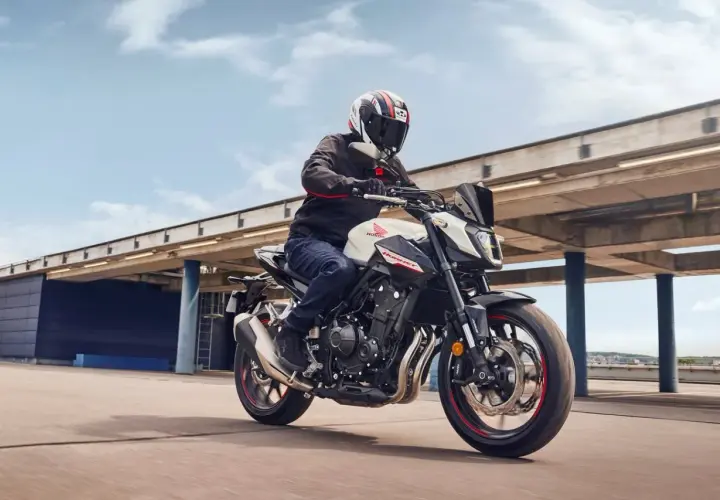 Hombre en moto Honda Hornet blanca y negra, con casco, acelerando. El motor de la moto ratea al acelerar, pero la experiencia es emocionante.