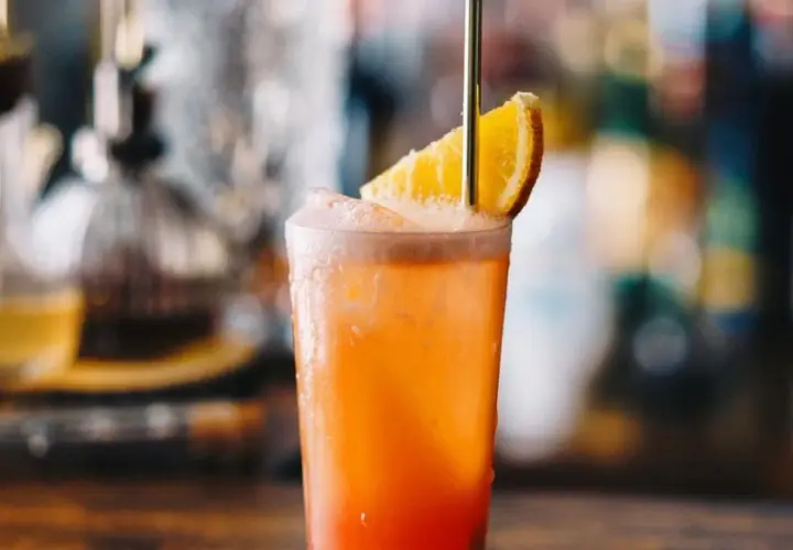 Orzeźwiający drink Garibaldi z plasterkiem pomarańczy i złotą słomką, idealny na letnie popołudnie.