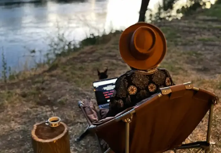 Praca zdalna nad rzeką. Kawa na pniu, piesek i laptop. Tak wygląda życie digital nomad co to znaczy?