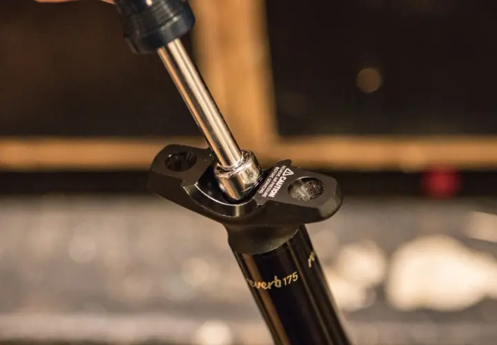 A socket wrench tightens a bolt on a Reverb Stealth dropper post.