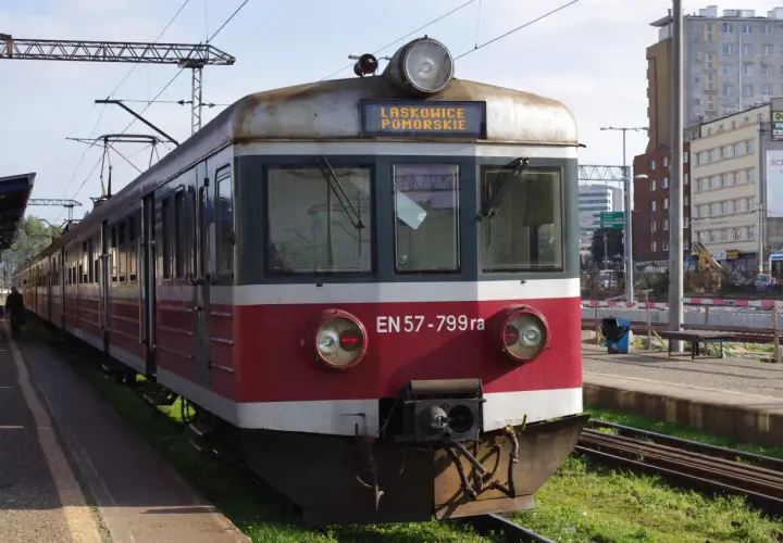 Pociąg EN57-799ra z napisem LASKOWICE POMORSKIE na tablicy. Stoi na peronie, w tle budynki i trakcje kolejowe.