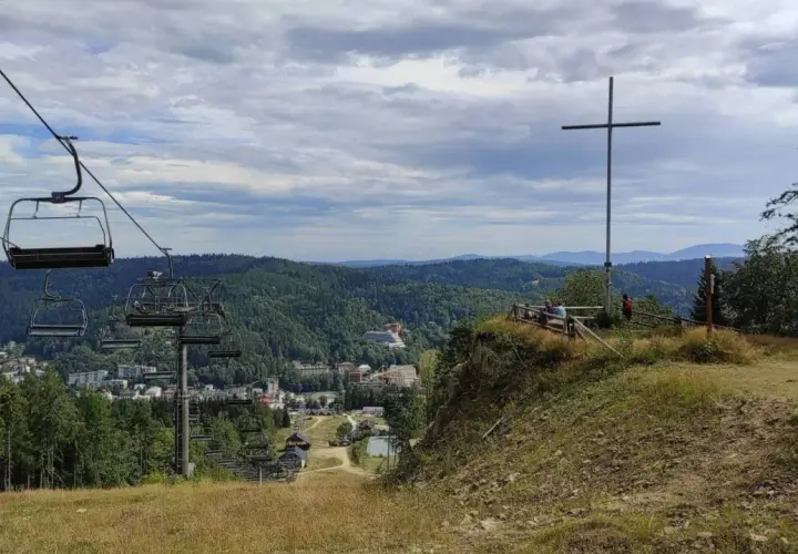 Widok z góry krzyżowej na dolinę z wyciągiem krzesełkowym i zabudowaniami.