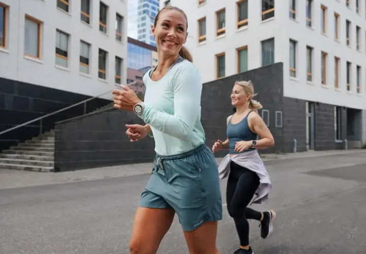 Dwie kobiety biegają po mieście, przygotowując się do treningu ultramaraton 50 km. Uśmiechnięte, pełne energii.