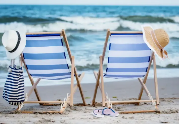 Dwa leżaki na plaży, gotowe na idealny weekend nad morzem. Słońce, szum fal i relaks czekają.