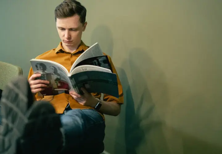 Młody mężczyzna czyta książkę, zastanawiając się, jakie książki z nurtu cli-fi warto przeczytać w 2026.