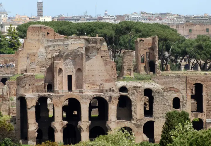 Antiche rovine del **Monte Palatino a Roma**, con archi imponenti e mura di mattoni che si stagliano contro il cielo azzurro.