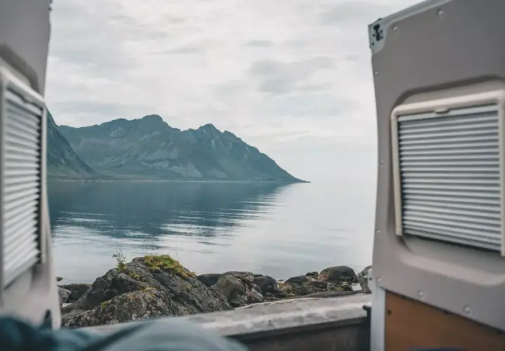Widok z kampera na spokojne morze i góry w Norwegii. Idealne miejsce na podróż kamperem.