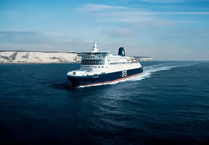 Duży prom DFDS płynie po wzburzonym morzu w kierunku białych klifów. To widok na trasie do Dunkierki.