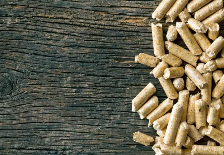 Drewniane deski i stos pelletu. Czy pellet jest ekologiczny? To pytanie zadaje sobie wielu, a ten obrazek pokazuje jego naturalne pochodzenie.