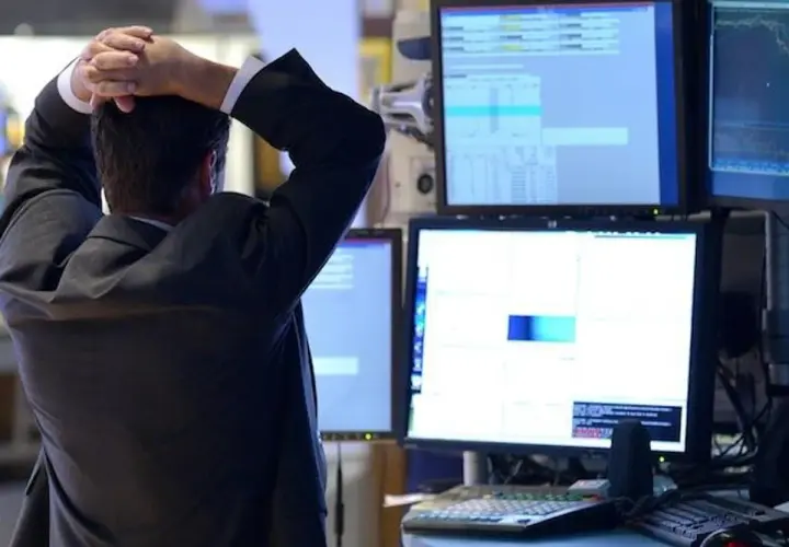 Zestresowany trader z rękami na głowie obserwuje wykresy, które mogą wskazywać na odwróconą krzywą rentowności.
