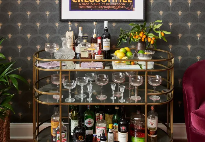 A stylish bar cart with bottles, glassware, lemons, and kumquats, offering inspiration on how to style a bar cart for a sophisticated home bar.
