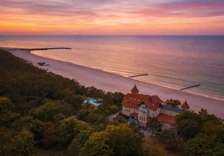 Zachód słońca nad Bałtykiem, malowniczy dworek i plaża. Idealne miejsce na wakacje w Polsce.