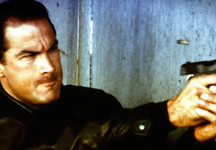 Steven Seagal jako Nico, policjant z filmu "Nico - ponad prawem", celuje z pistoletu.