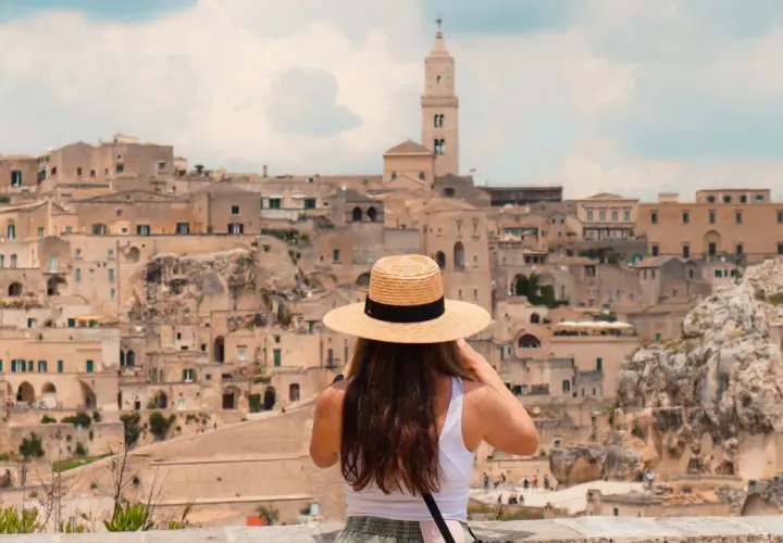 A woman in a straw hat takes in the ancient city of Matera, a highlight of any southern Italy trip itinerary.