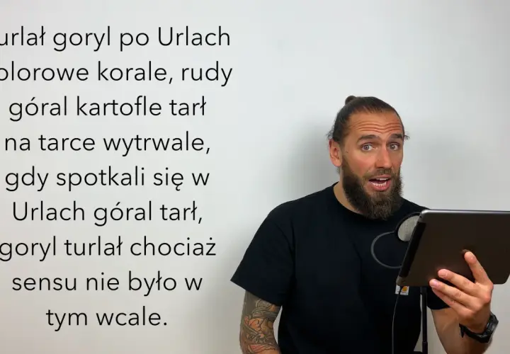 Mężczyzna z brodą i kitką czyta tekst o japońskich łamańcach językowych, gdzie goryl turlał się po Urlach, a góral tarł kartofle.