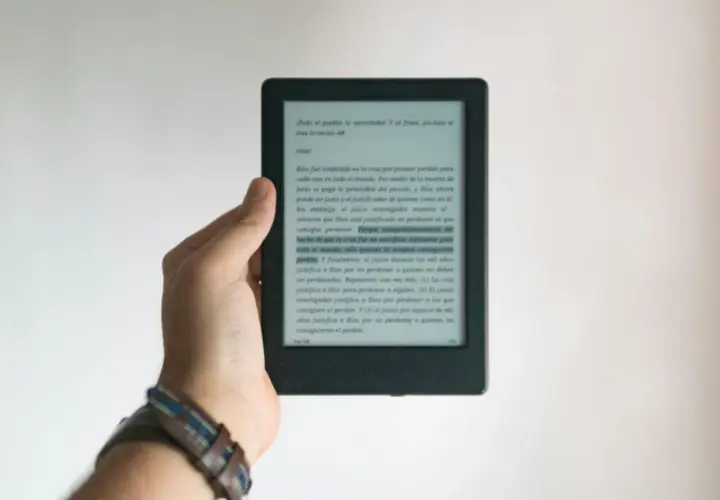 Dłoń trzyma czytnik e-booków. Tekst na ekranie dotyczy zasad ochrony praw autorskich przy wydawaniu e-booków.