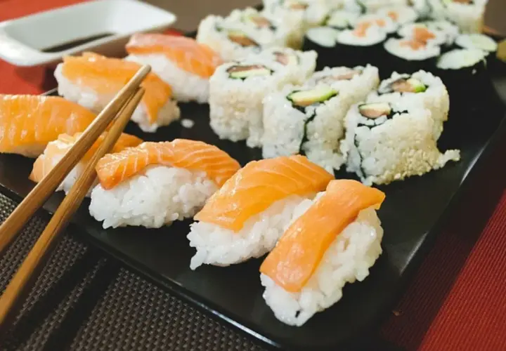 Pyszne sushi na diecie: nigiri z łososiem i rolki z awokado na czarnej tacy, gotowe do spożycia.