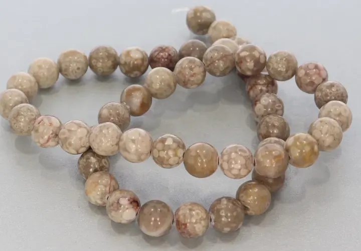 Zwei Stränge mit runden, beige-braunen Korallenperlen, die die Bedeutung von Schutz und Heilung symbolisieren.