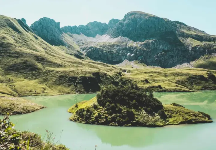 A serene lake reflects the rugged peaks of the Bavarian Forest. Perfect for **wandern im Bayerischen Wald**, this landscape offers a peaceful escape.