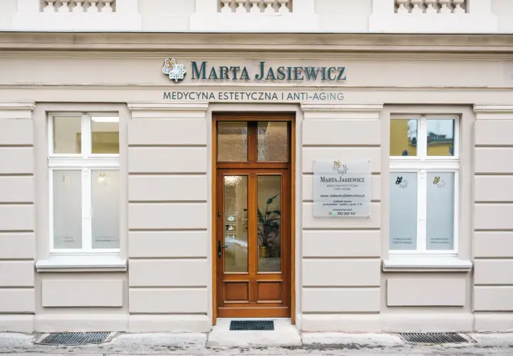 Elegancka fasada gabinetu medycyny estetycznej "Marta Jasiewicz" z drewnianymi drzwiami i oknami.
