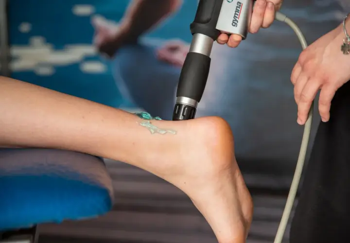 Terapia falą uderzeniową: aplikator z żelem na łydce pacjenta, przygotowanie do zabiegu.