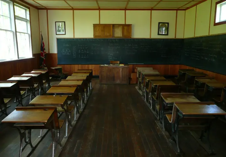 Klasa szkolna z ławkami i tablicą, gdzie widnieje statut szkoły.