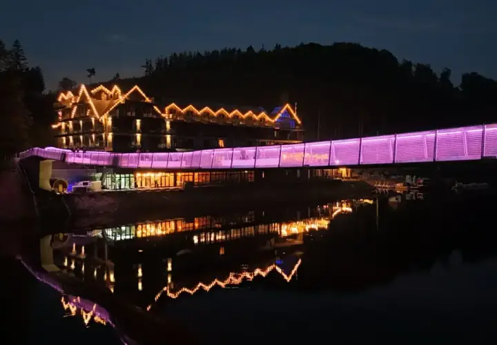 Widok na hotel z mostem oświetlonym na fioletowo, idealny na jedne z **ciekawe miejsca do 100 km od Katowic**.