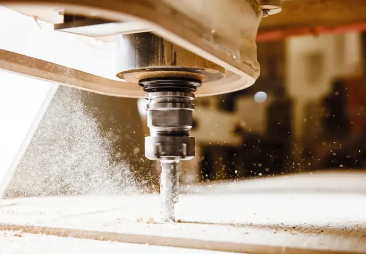 Precyzyjny frez CNC w akcji, tworzący drobny pył podczas obróbki drewna.