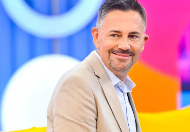 Krzysztof Ibisz, znany z programów telewizyjnych, uśmiecha się w beżowej marynarce. Jego wiek dodaje mu charyzmy.
