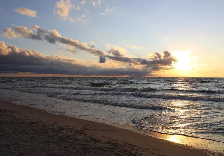 Zachód słońca nad Bałtykiem, złote fale obmywają piaszczystą plażę. Idealne miejsce na kąpielisko na mierzei helskiej.