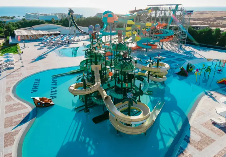 Kolorowy aquapark Fantazia Resort Marsa Alam z licznymi zjeżdżalniami i basenami, w tle morze.