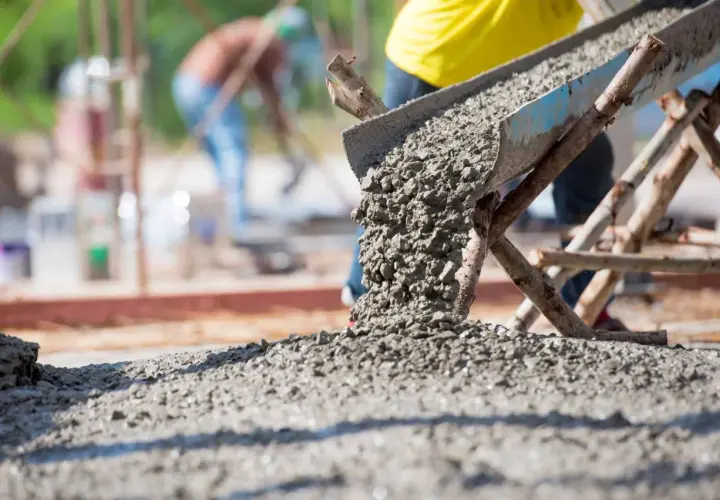 Beton wylewany z betoniarki na placu budowy. Obrazek ilustruje, jak obliczyć metry sześcienne betonu potrzebne do wylania fundamentów.