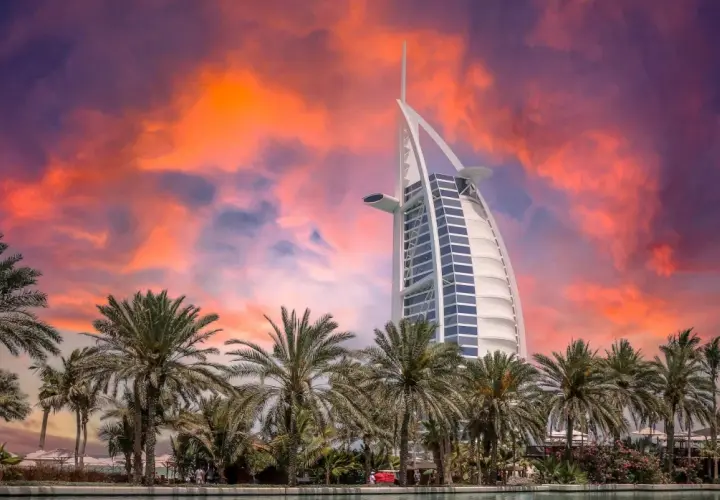 Zachód słońca nad Dubajem, palmy i hotel Burdż al-Arab. Zastanawiasz się, ile kosztuje wycieczka do Dubaju?