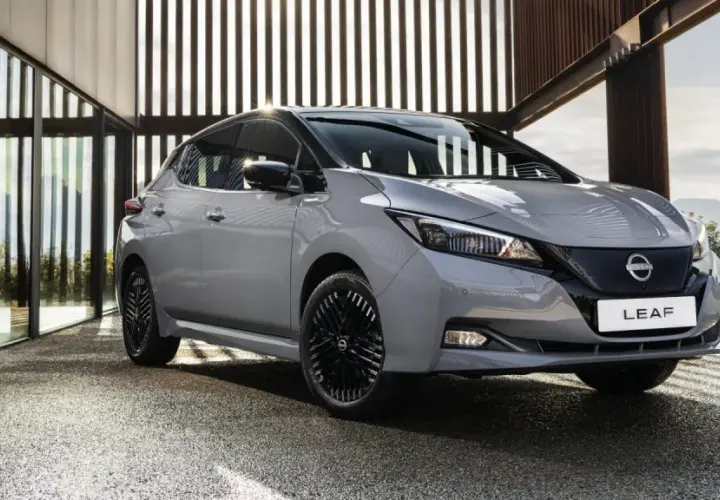 Szary Nissan Leaf stoi przed nowoczesnym budynkiem z przeszklonymi ścianami.