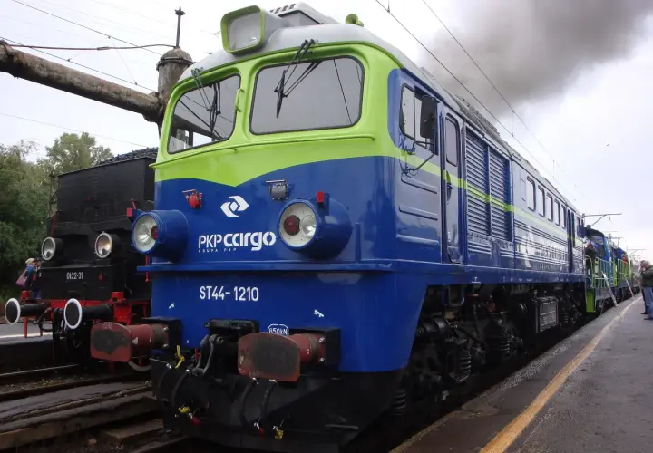 Lokomotywa ST44-1210 PKP Cargo, symbol Solidarności, dymi na tle parowozu.