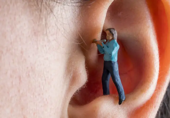 Kleine Figur im Ohr, die versucht, den Tinnitus zu bekämpfen. Vitamin B12 könnte helfen.