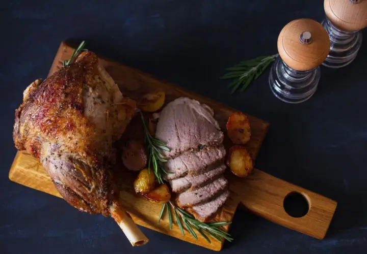 Pieczona jagnięcina z ziemniakami i rozmarynem na desce.