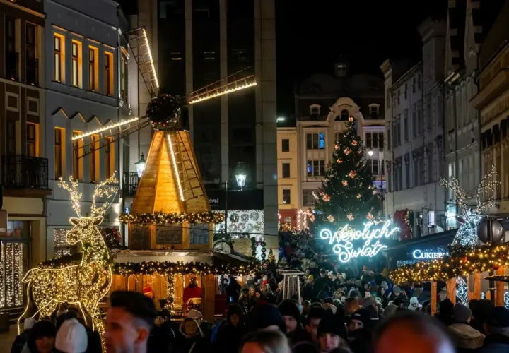Tłum ludzi na jarmarku bożonarodzeniowym w Kujawsko-Pomorskiem. Świecący renifer, drewniany wiatrak i choinka tworzą magiczną atmosferę.