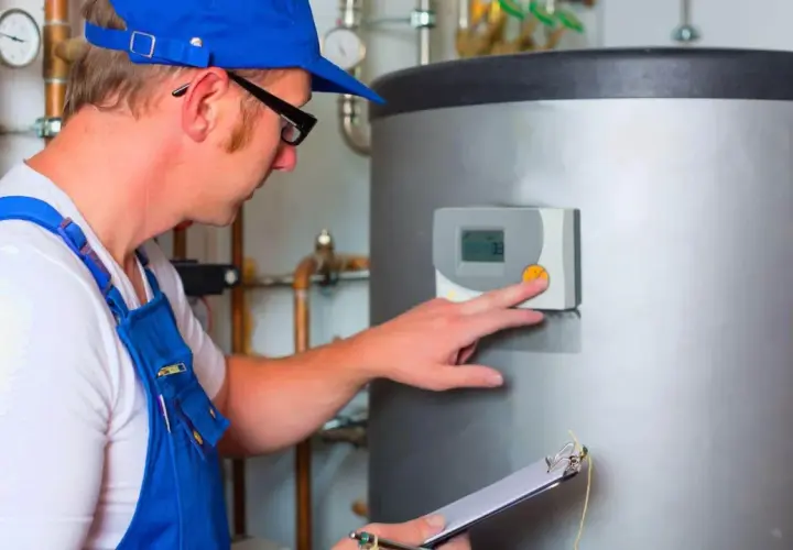 Instalacja ogrzewania gazowego: monter sprawdza panel sterowania bojlerem, notując dane na kartce.
