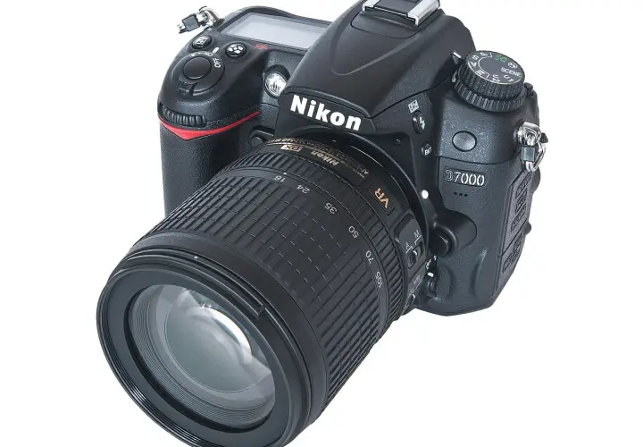 Nikon D7000 z obiektywem 18-105mm VR. Aparat cyfrowy z widocznymi przyciskami i pokrętłem trybów. Dane techniczne tego modelu są imponujące.
