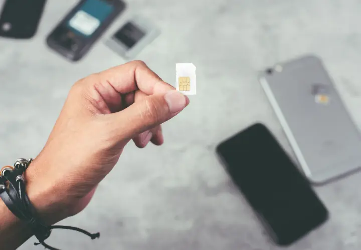 Dłoń trzyma kartę SIM, gotową do włożenia do telefonu. To idealne rozwiązanie dla osób szukających internetu na kartę bez umowy.