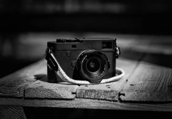 Klasyczny aparat Leica M10 Monochrom z obiektywem na drewnianym blacie.
